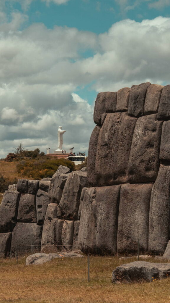 Muros gigantes de piedra caliza en zigzag de la fortaleza de Sacsayhuamán bajo un cielo andino nublado.