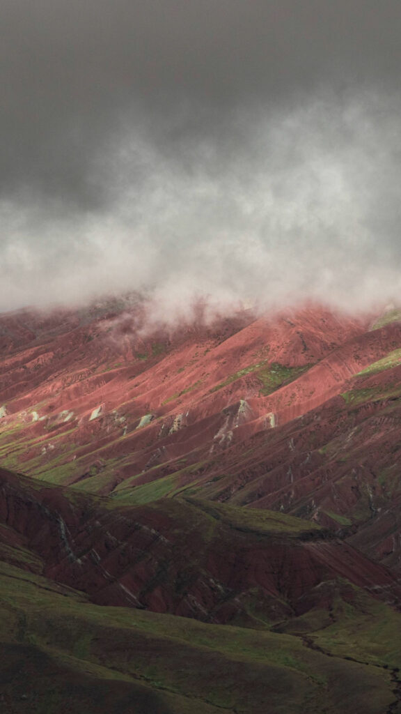 Una vista en primer plano de las franjas minerales diagonales de la Montaña de Siete Colores con una ligera capa de nieve en las cumbres.