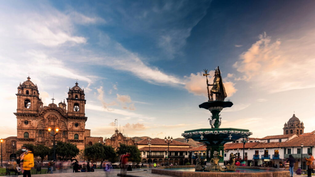 Una toma panorámica amplia de la Plaza de Armas de Cusco, con la fuente central y la Iglesia de la Compañía de Jesús.