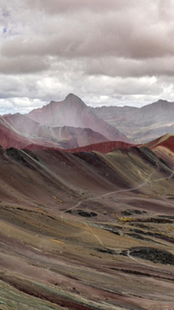 Una vista de cerca de las franjas minerales diagonales de la Montaña de Siete Colores con una ligera capa de nieve en las cumbres.