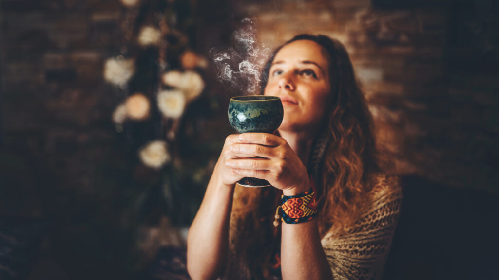 Una mujer sosteniendo una copa ceremonial con vapor, con los ojos cerrados en meditación durante un retiro espiritual en el Manu.