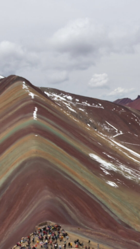 Una vista de un paisaje dramático con colinas de color rojo intenso, parcialmente cubiertas por nubes bajas y neblina.